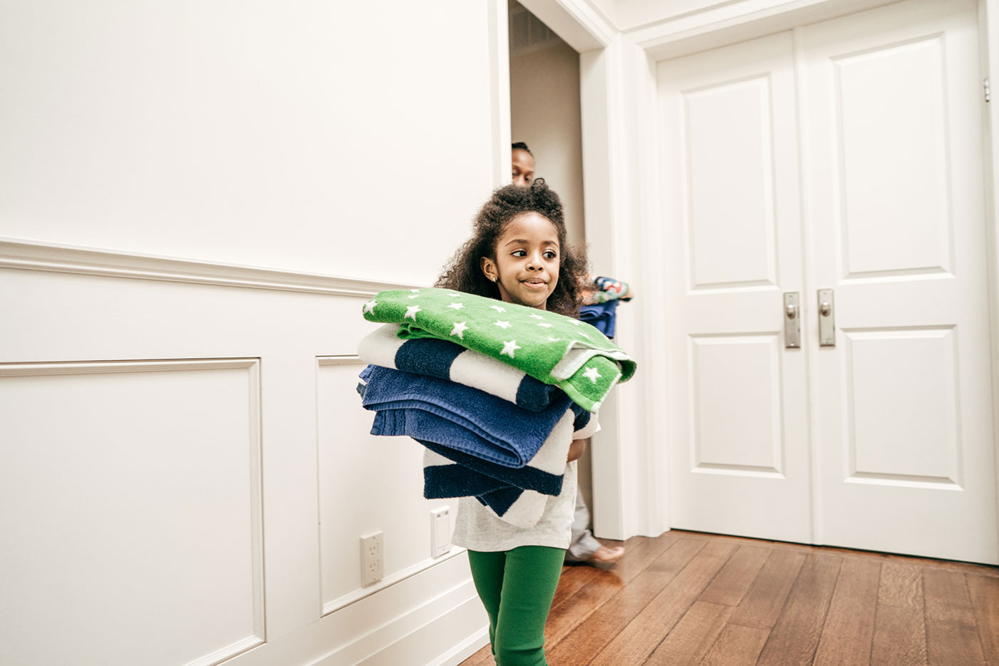 Young girl carrying a stack of folded towels