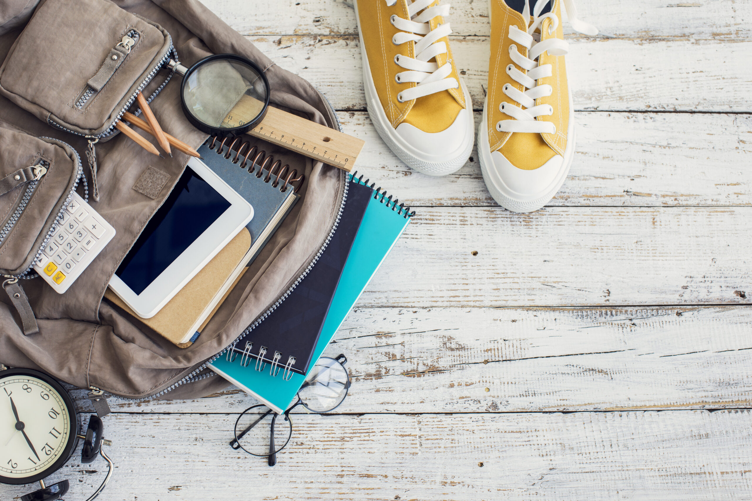 Brown backpack with notebooks peeking out and yellow sneakers