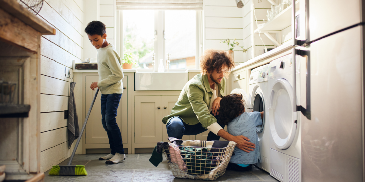 Father and 2 sons help each other clean up a laundry room